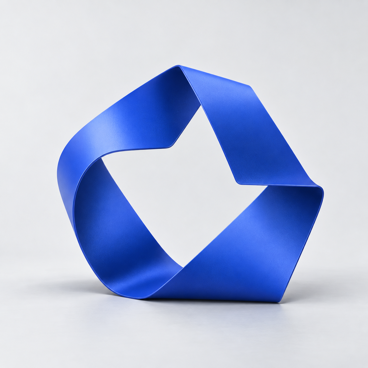 Cobalt-blue folded ribbon sculpture on a light grey studio background